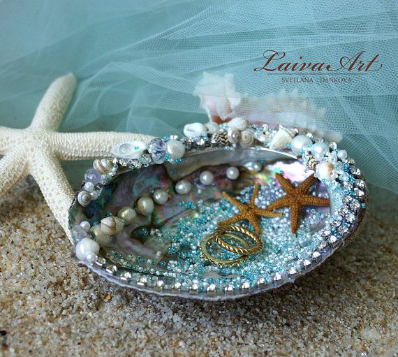 there is a shell with pearls and other things in it on the sand next to a starfish