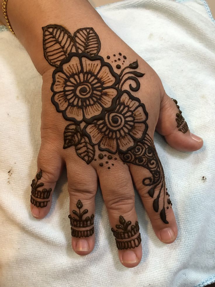 a woman's hand with henna tattoos on her left hand and flowers on the other