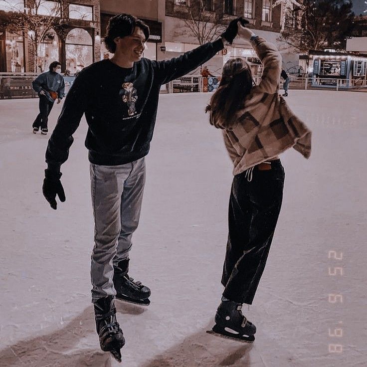 two people standing in the snow with their arms around each other while one person holds his hand up