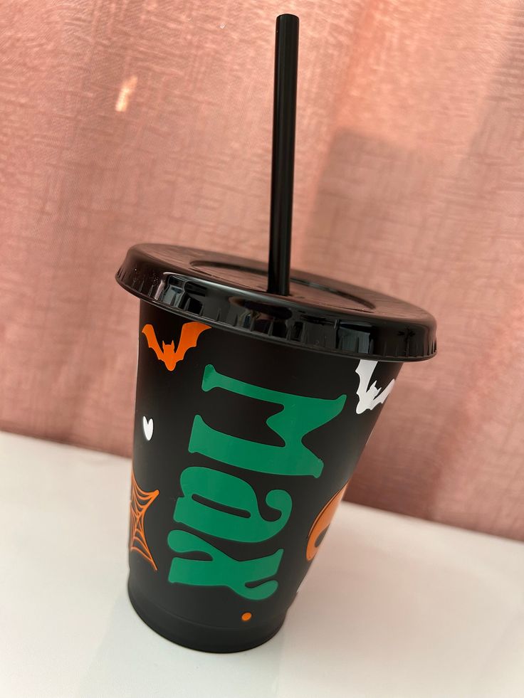 a black cup with green and orange designs on it