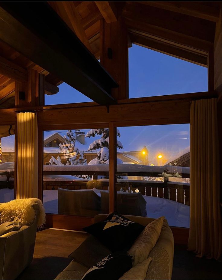 a living room filled with furniture next to a window covered in snow at night time