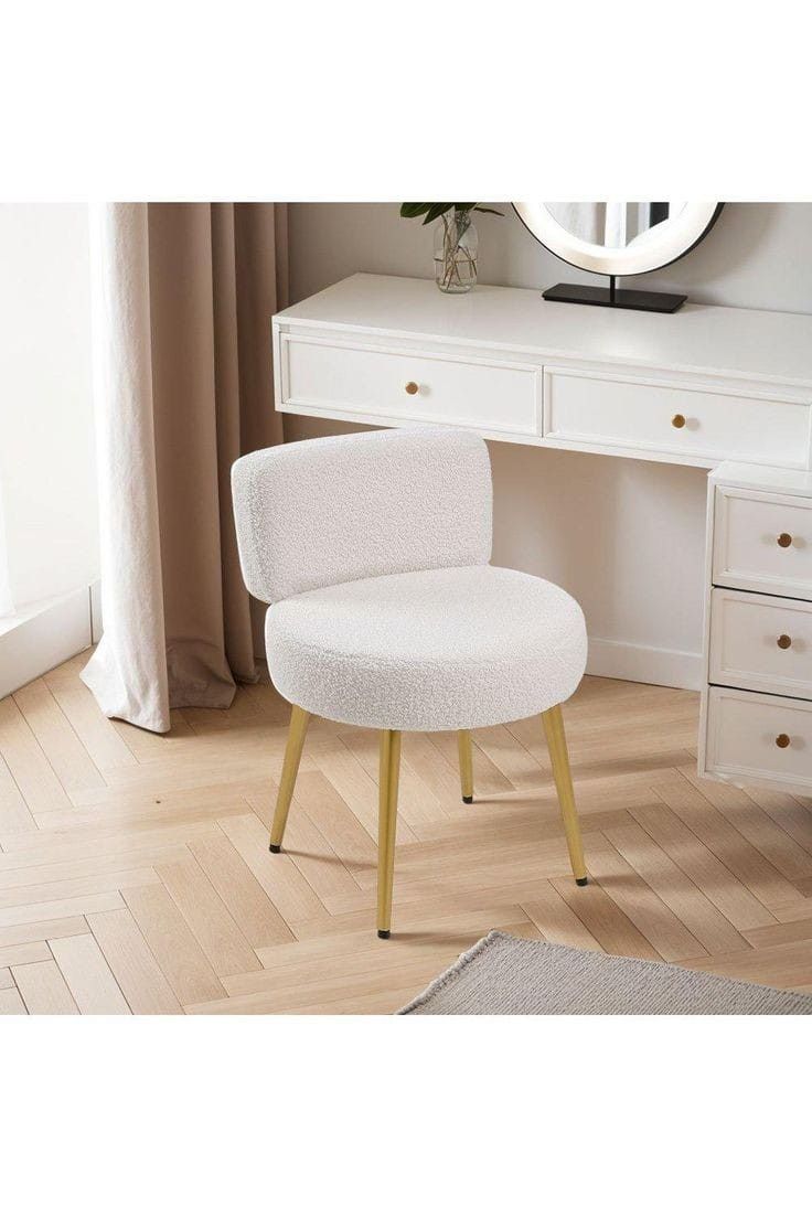 a white chair sitting on top of a hard wood floor next to a dresser and mirror