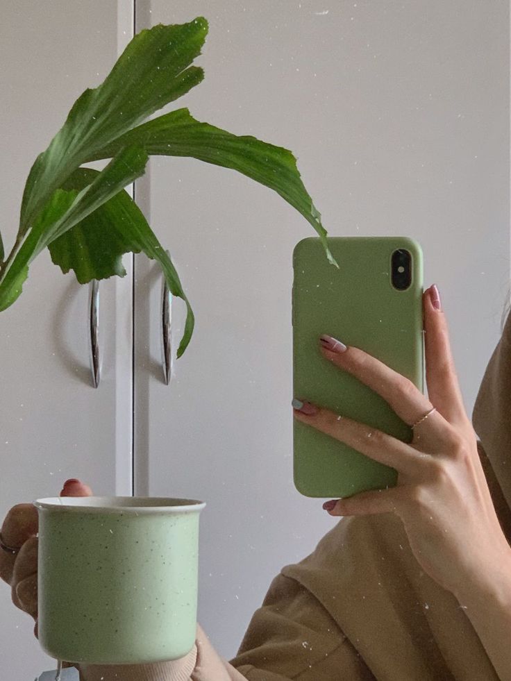 a woman taking a selfie with her phone in front of a potted plant