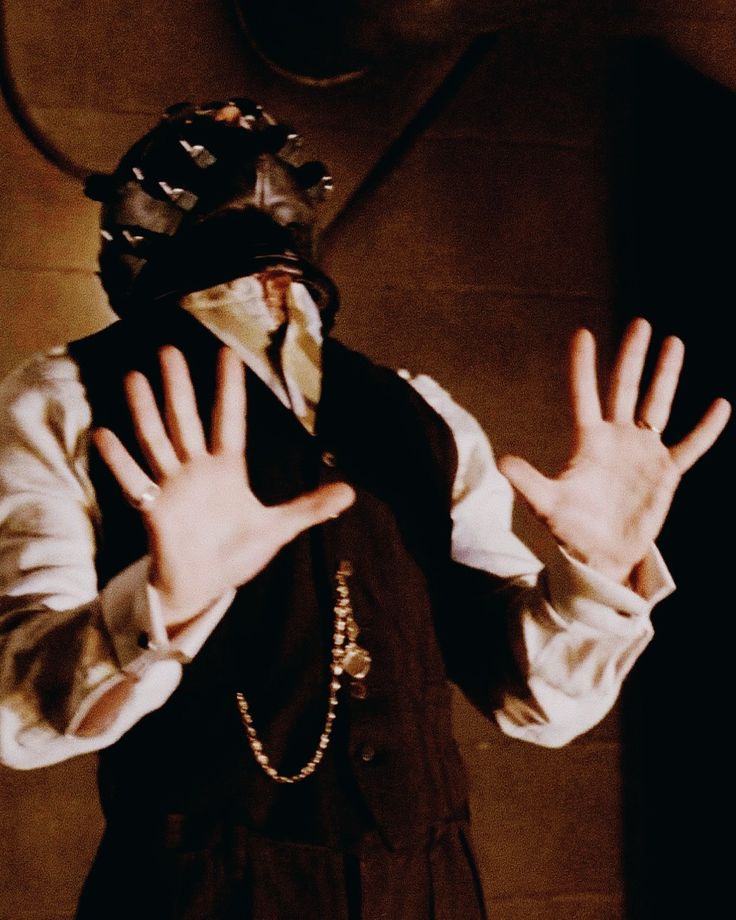 a man wearing a mask and holding his hands up