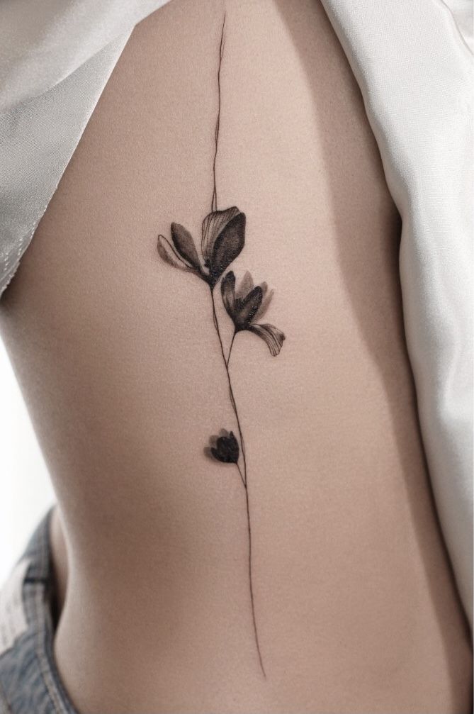 the back of a woman's stomach with a flower tattoo on it