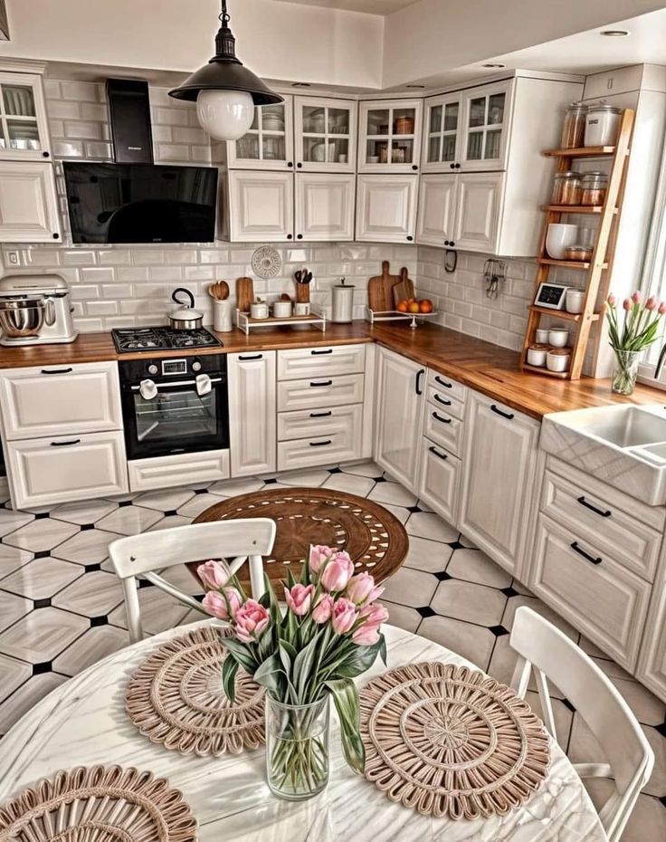 a kitchen filled with lots of white cabinets and counter top space next to a dining room table