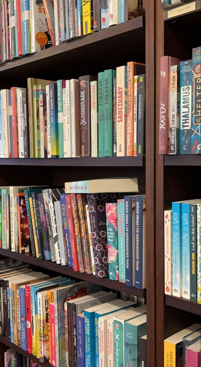 a bookshelf filled with lots of different colored books on top of wooden shelves