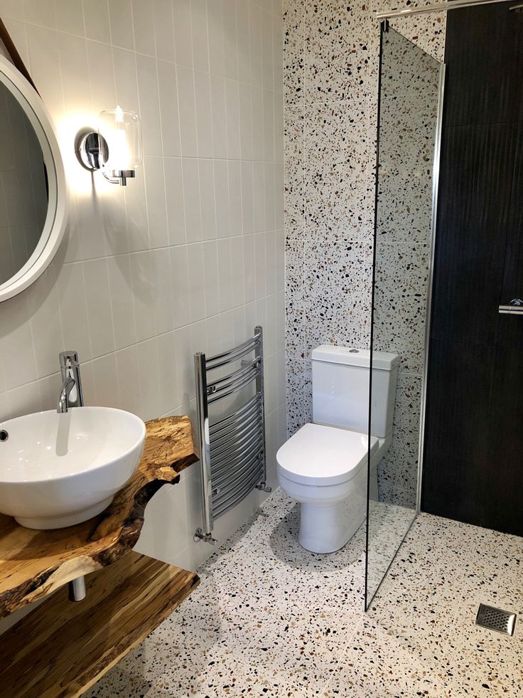 a white toilet sitting next to a sink in a bathroom under a mirror and towel rack