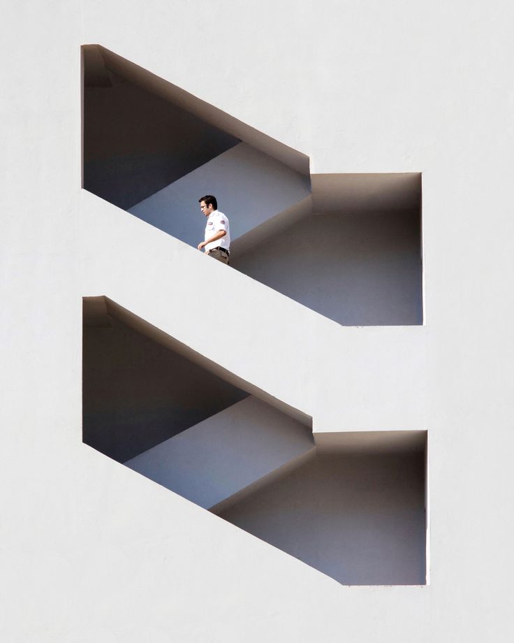 a man is standing in the middle of two white buildings that are shaped like rectangles