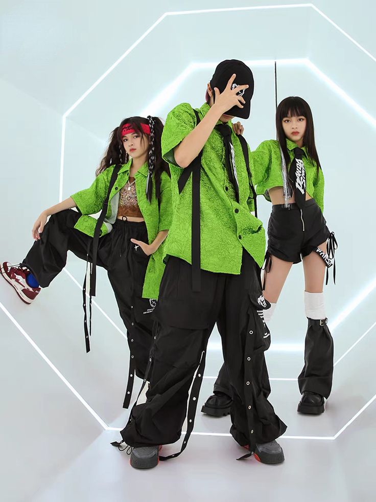 three young people dressed in green and black are posing for a photo while holding their cell phones up to their ears