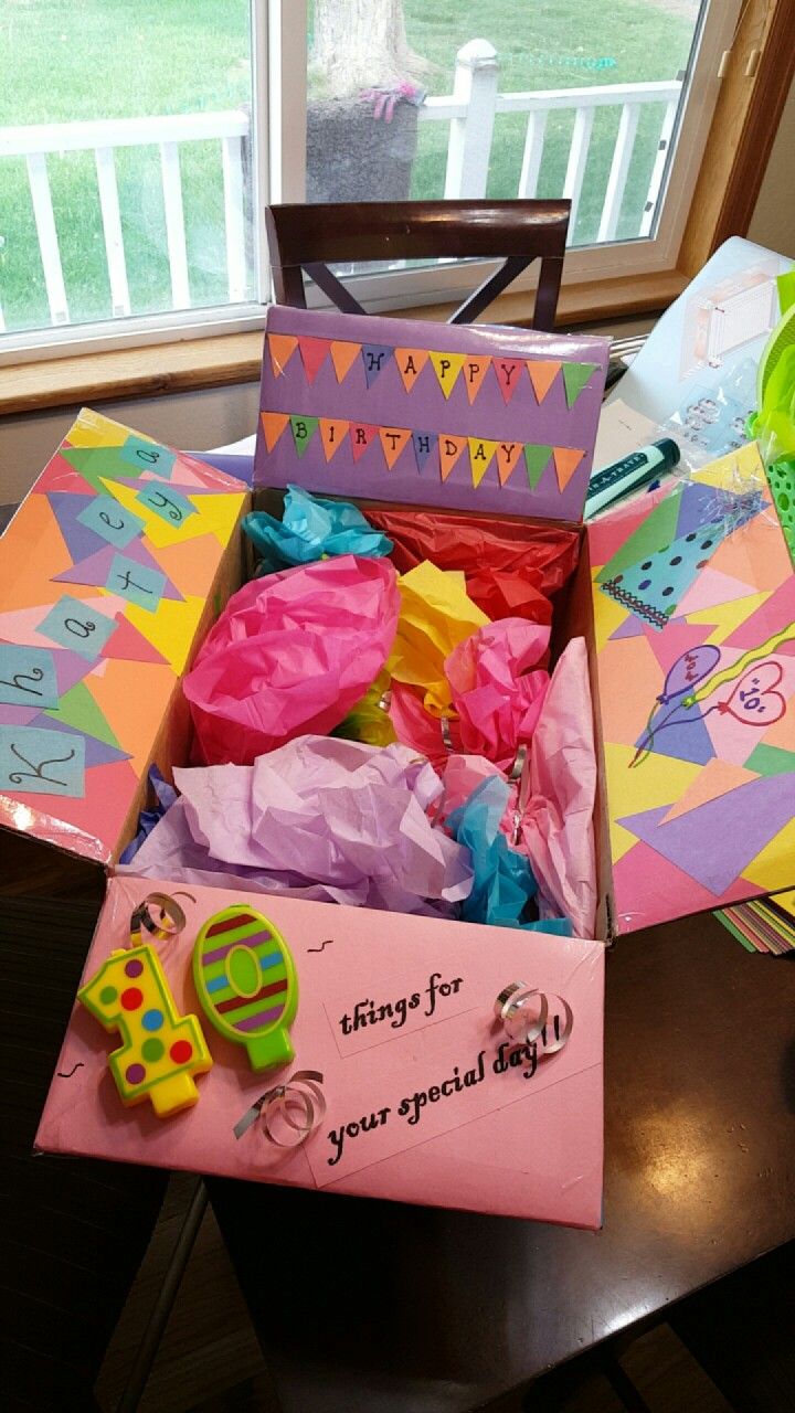 an open birthday box on a table in front of a window with decorations and streamers