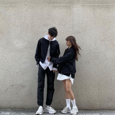 a man and woman standing next to each other near a wall with their arms around each other