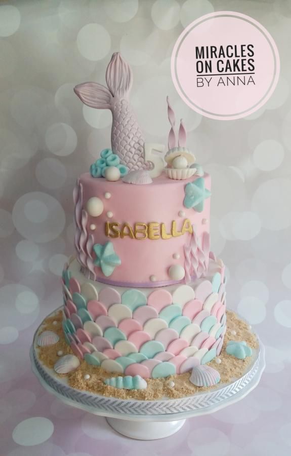 a pink and blue cake with mermaid decorations