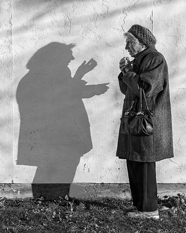 an old man standing in front of a wall with his shadow cast on the wall