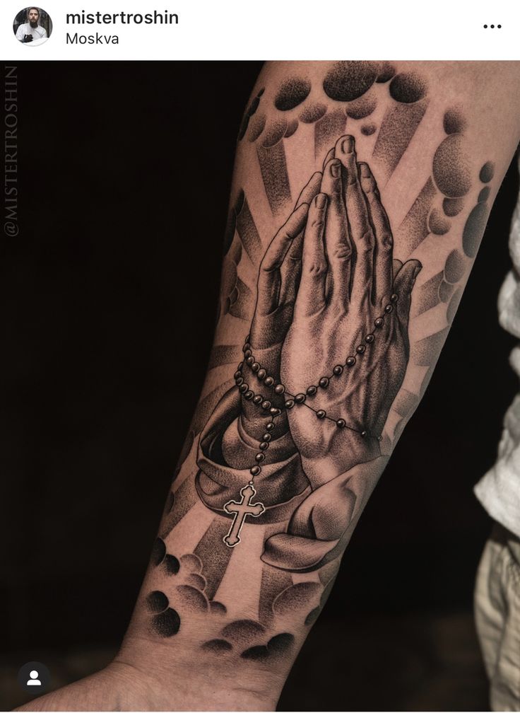 a person with a rosary and praying hands tattoo on their arm is holding the cross