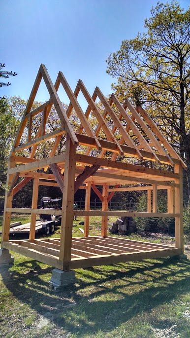 a wooden structure sitting in the middle of a field next to some trees and grass