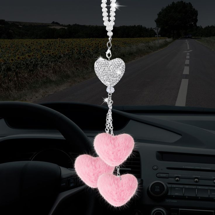 two pink hearts hanging from the dashboard of a car