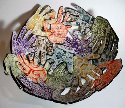 a bowl with many different colored fish on it's sides and hands in the middle