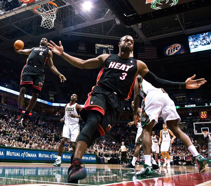 a basketball player is going to dunk the ball in front of two other players