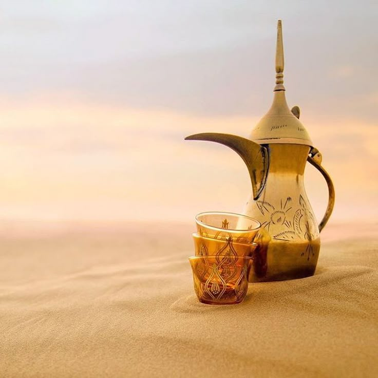 a tea pot and cup sitting on the sand