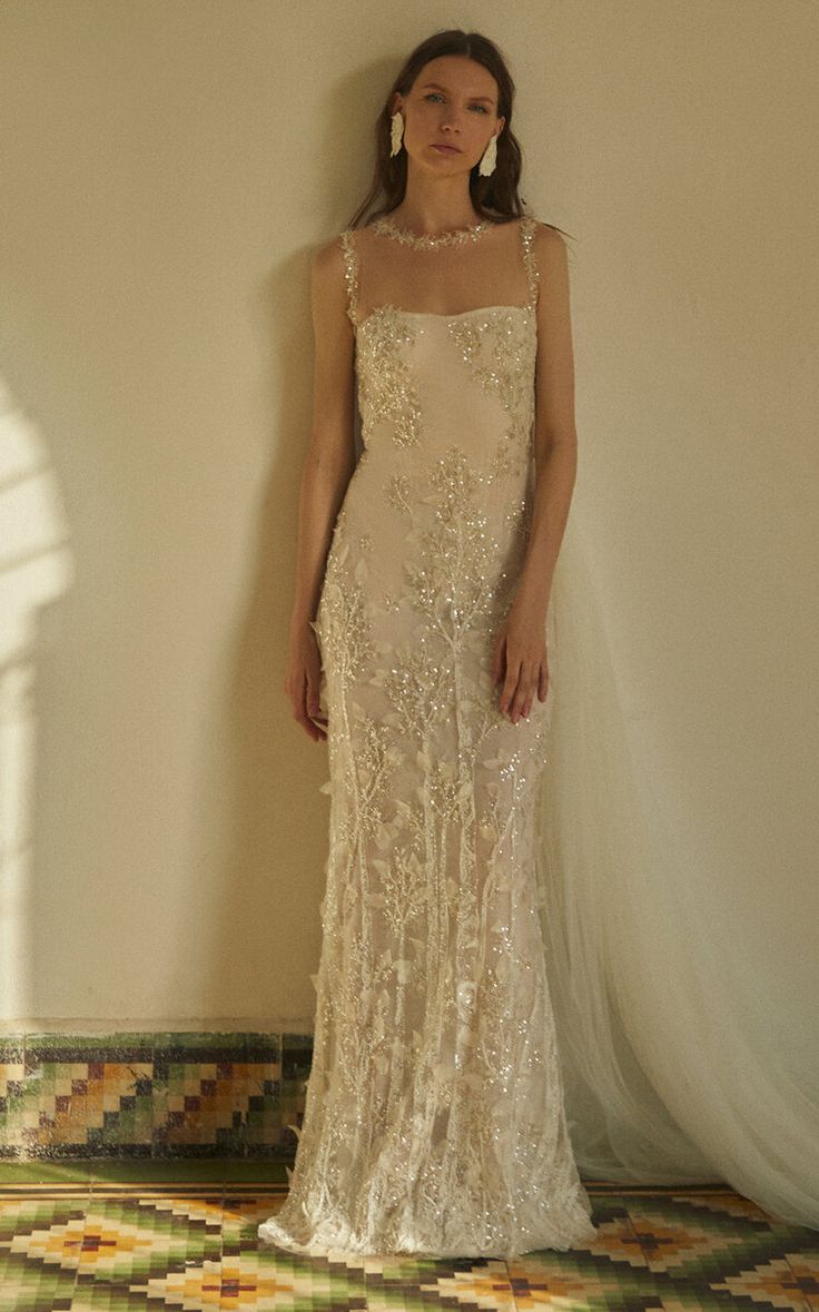 a woman standing in front of a wall wearing a dress with beading on it