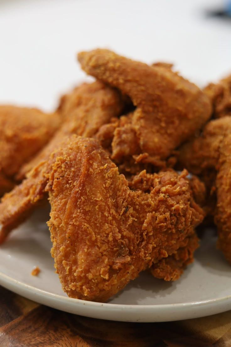 fried chicken on a white plate sitting on a table