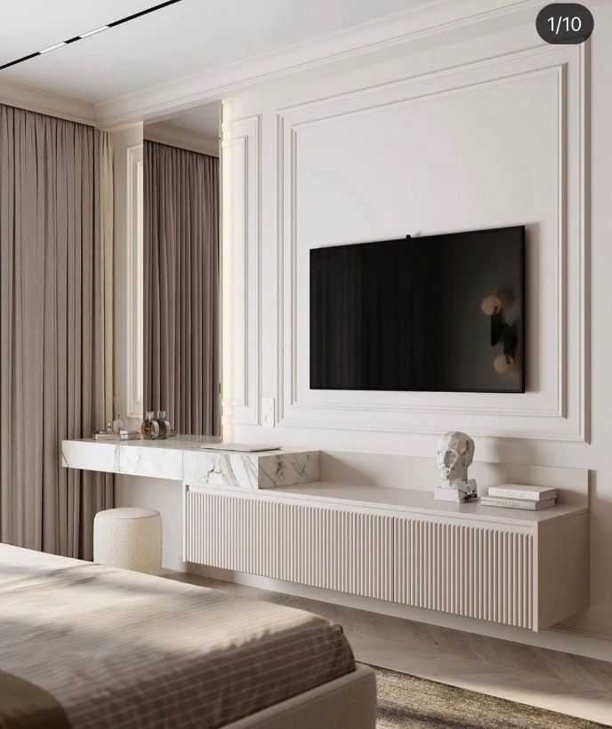 a large flat screen tv mounted to the side of a white wall in a bedroom