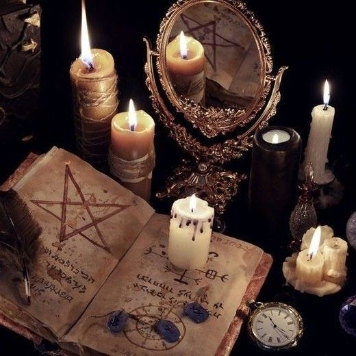 an open book surrounded by candles and other items