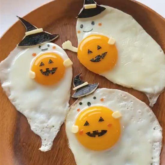 three fried eggs with faces drawn on them in the shape of jack - o'- lanterns