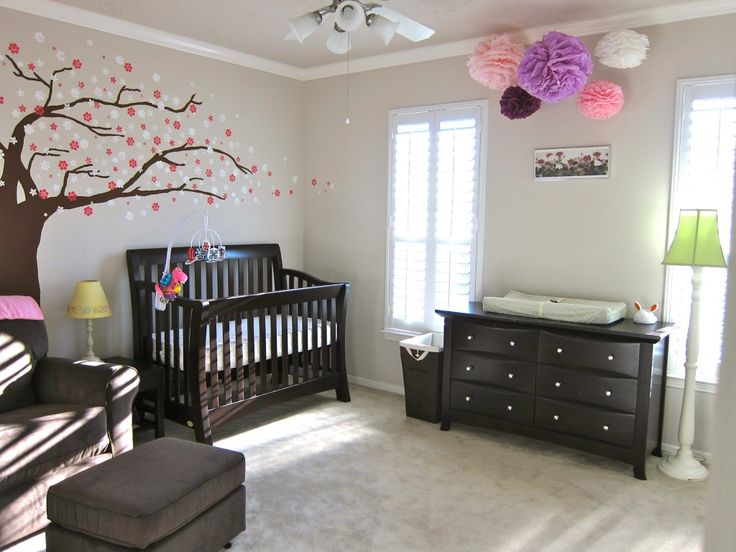 a baby's room decorated in shades of pink, purple and white with a tree painted on the wall