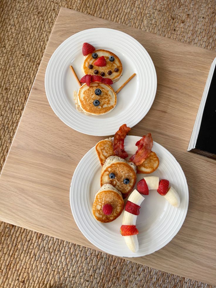 two white plates topped with pancakes and fruit