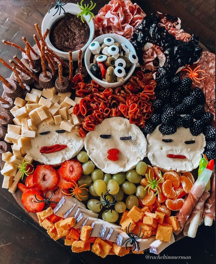 a platter filled with cheeses, crackers, fruit and other food items