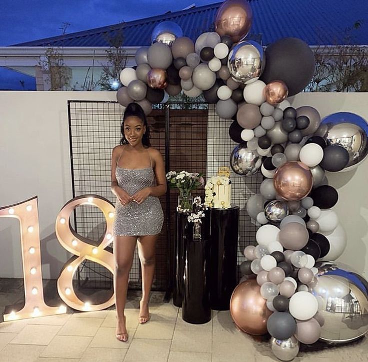 a woman standing in front of a giant balloon arch with the letter b on it