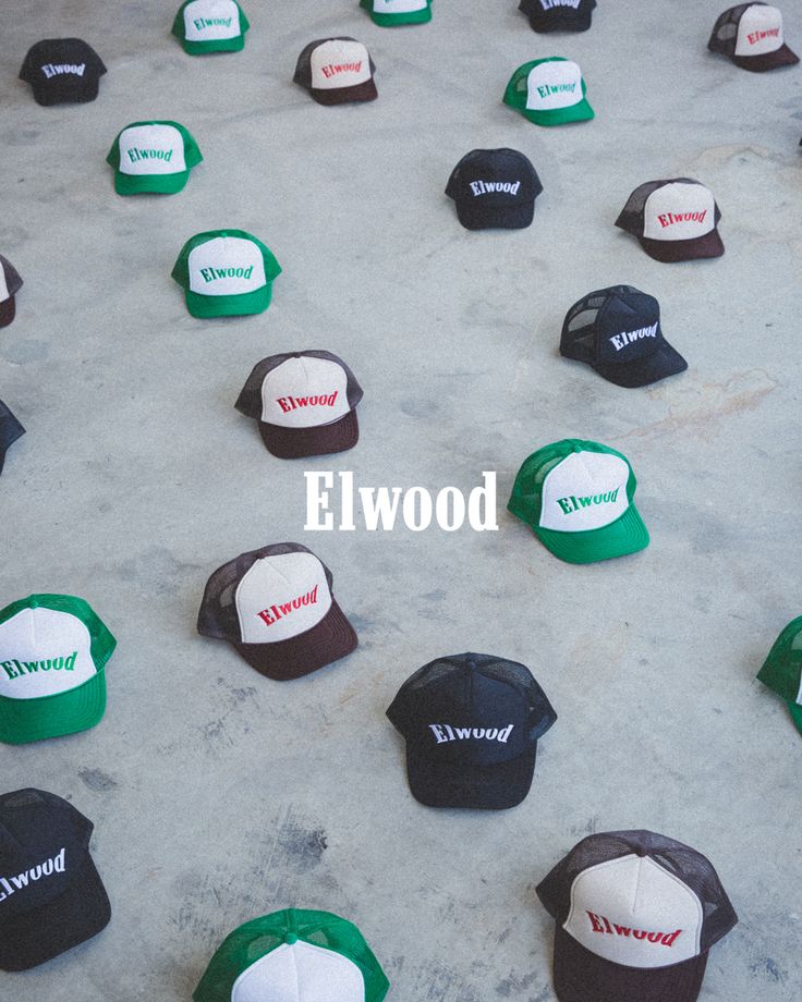 several hats sitting on the ground with words that say elwood in white and green