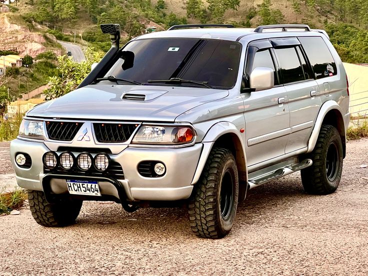 a silver suv parked on top of a dirt road