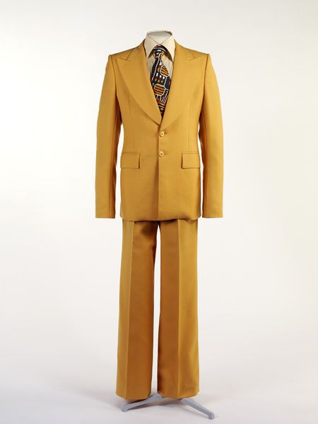 Man's suit | Victor Herbert | Great Britain, United Kingdom, 1974 | Material: wool | Herbert uses traditional tailoring techniques combined with flamboyant details of cut and colour typical of 1970's British menswear | VA Museum, London Mens Suits Ideas, Colourful Suit, 70s Fits, 70s Suit, Theater Poster, Retro Suits, 70s Men, Fashion 1970s, Yellow Suit