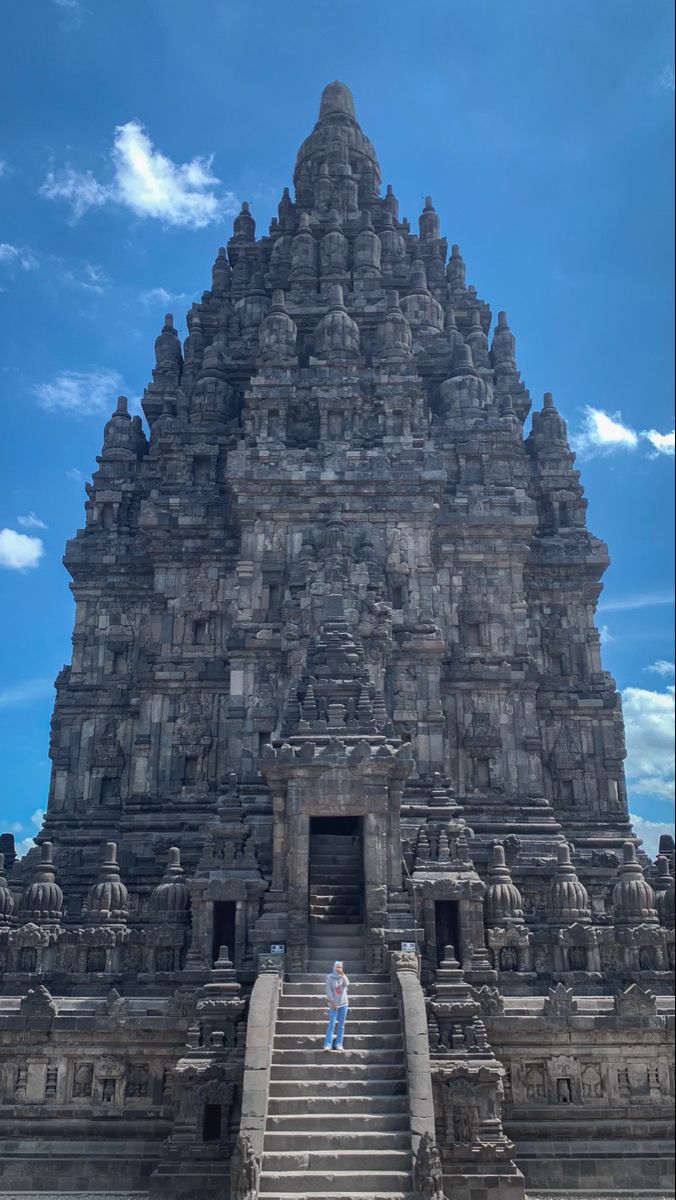 a person standing in front of a very tall building with many steps leading up to it