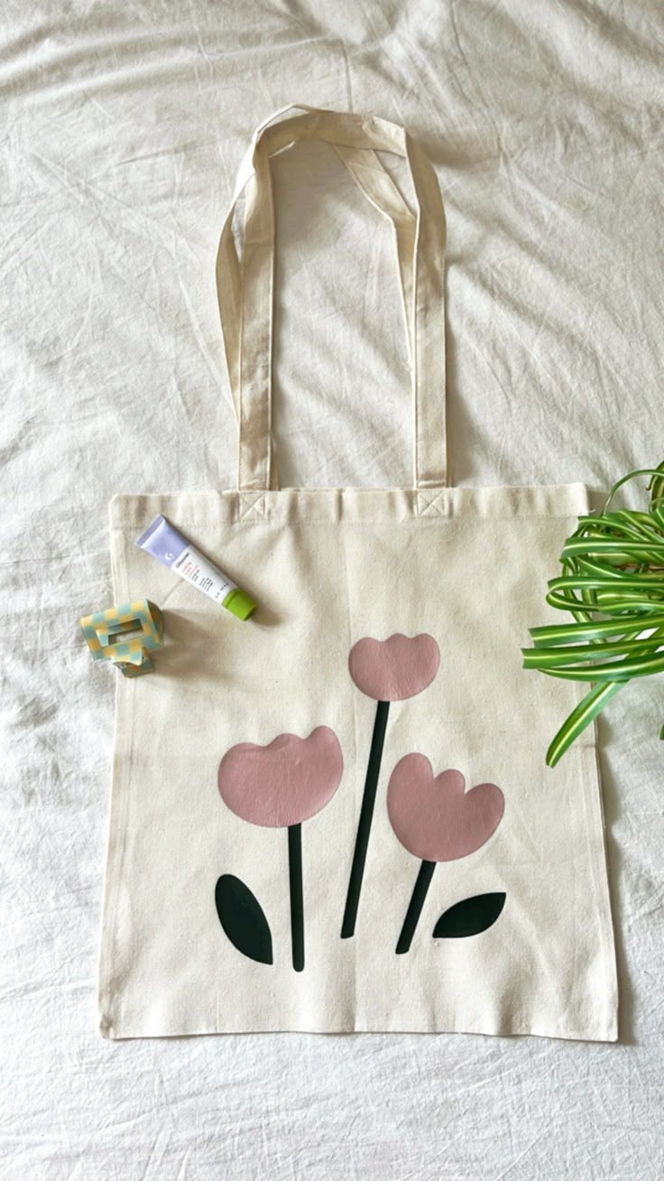 a white bag with pink flowers on it next to some green plants and a tube of toothpaste