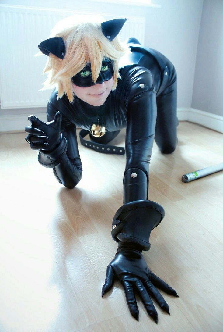 a woman in black catsuit laying on the floor with her hands up to her chest