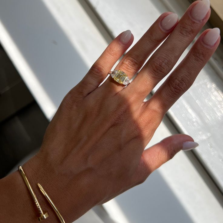 a woman's hand with a yellow diamond ring on top of her left hand