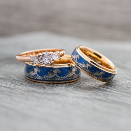 two gold and blue wedding rings with diamonds on them sitting on top of each other