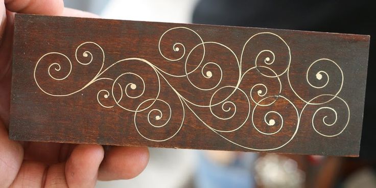 a person holding up a piece of wood with swirl designs on the outside of it