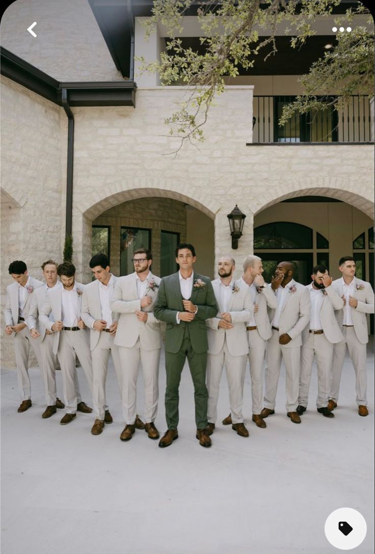 a man standing in front of a group of men wearing white suits and ties with their arms around each other