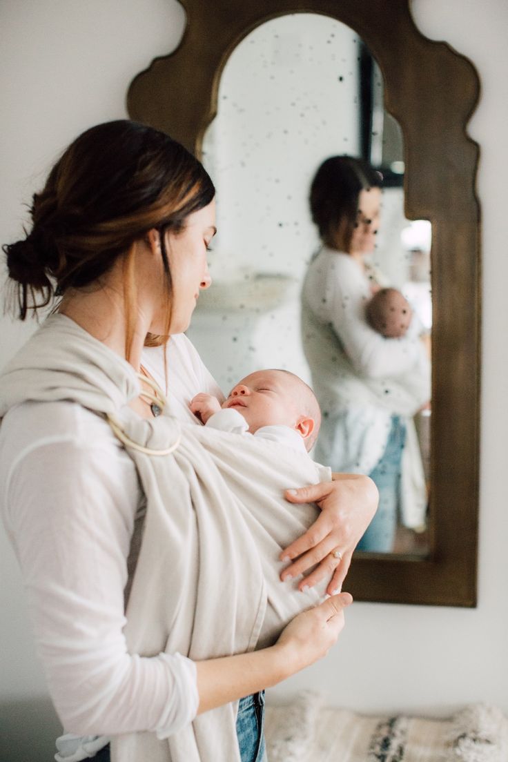 a woman holding a baby in front of a mirror