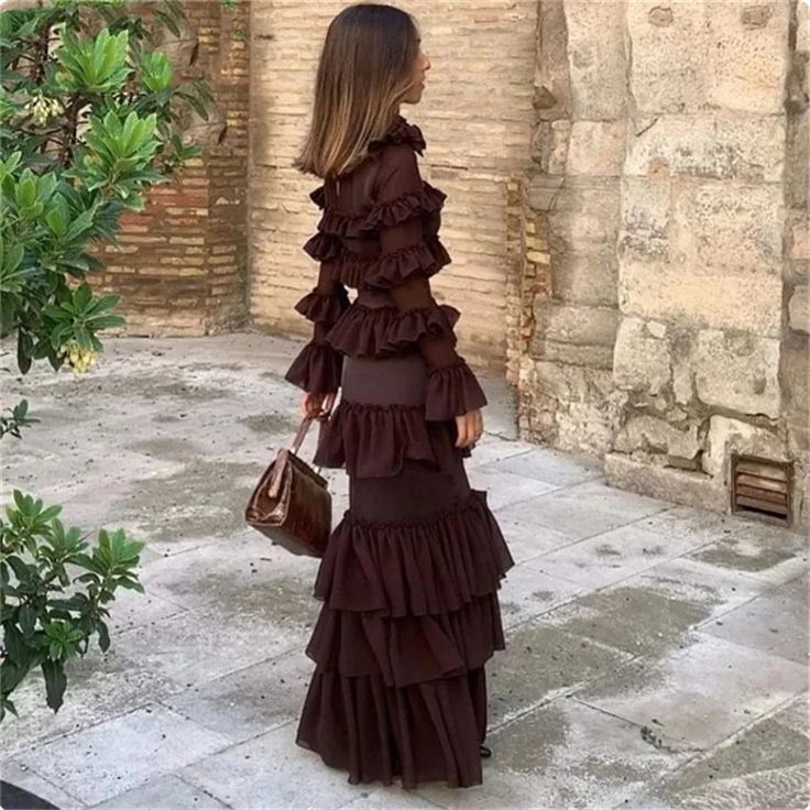 a woman in a brown dress is walking down the street with her hand on her hip