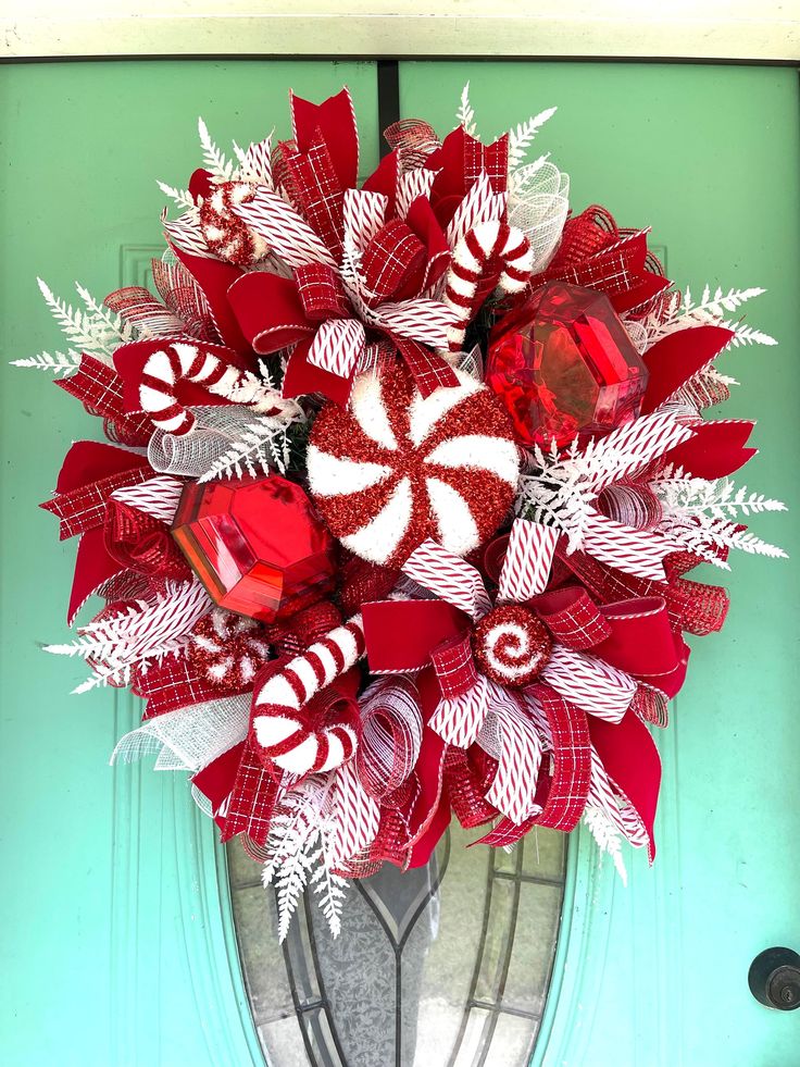 a red and white wreath with candy canes in it on a green front door