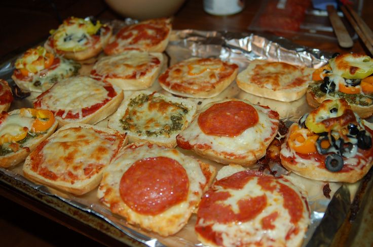 many small pizzas are sitting on tin foil and ready to be baked in the oven