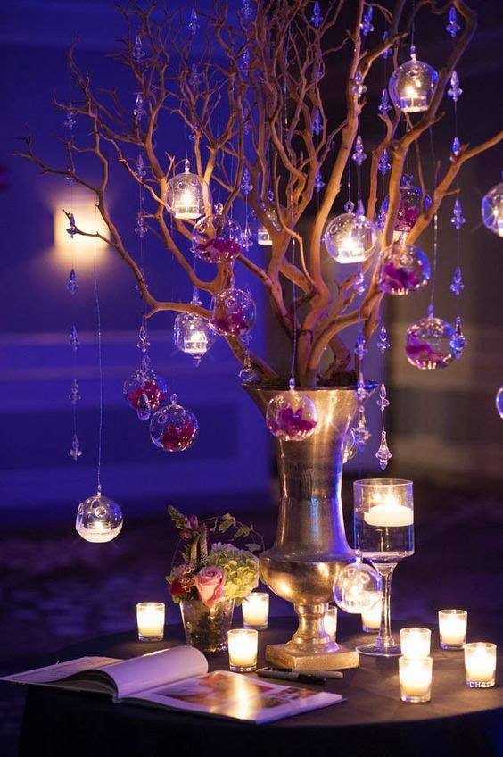 a vase filled with candles sitting on top of a table covered in glass balls and branches