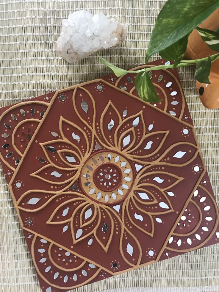 an intricately designed coaster sits next to a potted plant