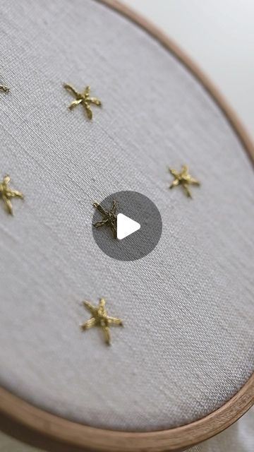 a close up of a cross stitch with gold stars on it